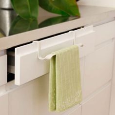 a green towel hanging on the side of a white cabinet