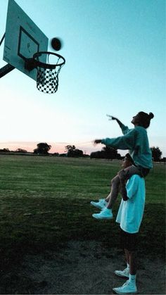 two people are playing basketball in the park at sunset or dawn, one is jumping up to catch the ball