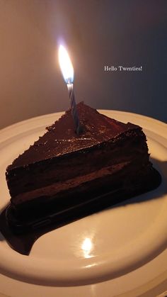 a piece of chocolate cake with a single candle on top is sitting on a plate