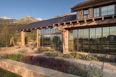 a large building with lots of windows next to a field and mountains in the background