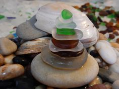 a stack of sea glass sitting on top of rocks next to other stones and pebbles