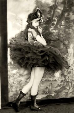 an old fashion photo of a woman in a tutu skirt and high heeled boots