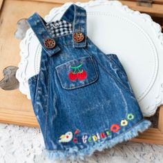 a pair of denim overalls with cherries on the back are sitting on a table