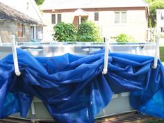 blue tarp on the back of a boat in front of a house and trees