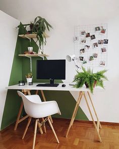 a desk with a computer on top of it next to a chair and potted plant