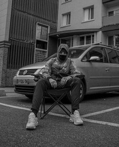 a man sitting in a chair next to a parked car