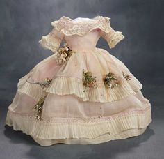 an old fashioned dress with flowers and lace on the bouncy, is displayed against a gray background