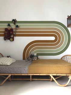 a small bed sitting in front of a wall with an abstract design on it's side