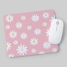 a pink mouse pad with white daisies on it and a yellow dot in the middle