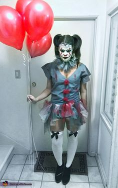 a woman dressed up as a clown with red balloons in her hand, standing next to an open door