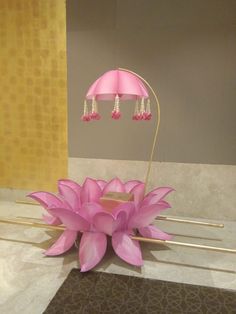 a pink flower sitting on top of a table next to a lamp and other items