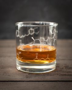 a glass filled with liquid sitting on top of a wooden table