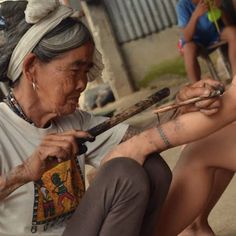 an old woman sitting on the ground holding a baseball bat and looking at her tattoo