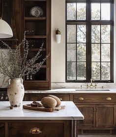 a kitchen with wooden cabinets and marble counter tops, along with a vase filled with flowers