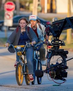 two people riding bikes down the street with a camera attached to it's handlebars