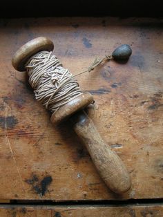 a spool of twine sitting on top of a wooden table next to a rock