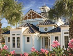 a blue and white house surrounded by palm trees