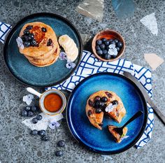 two plates with pancakes and blueberries on them