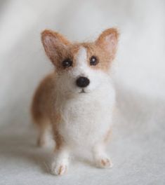 a small stuffed dog sitting on top of a white blanket next to a black nose