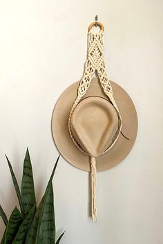 a hat hanging on the wall next to a potted plant