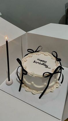 a birthday cake sitting on top of a white box with a lit candle in it