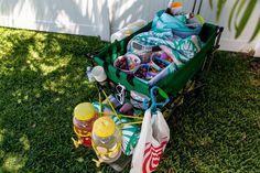 a green wagon filled with lots of items sitting in the grass