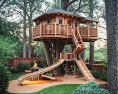 a large tree house with a slide in the middle of it's back yard