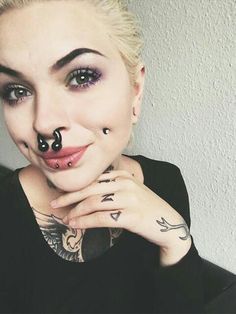 a woman with piercings on her nose and nose ring is posing for the camera