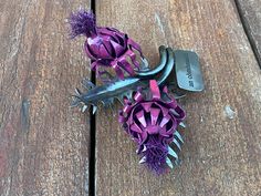 purple flowers are sitting on top of a wooden table next to a hair dryer