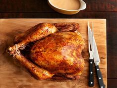 a roasted turkey on a cutting board with knifes