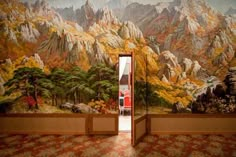 an open door leading to a scenic mountain scene with trees and mountains painted on the wall