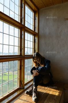 a woman sitting on the window sill looking at her cell phone - stock photo - images