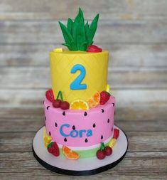 a two tiered cake decorated with fruit and pineapples