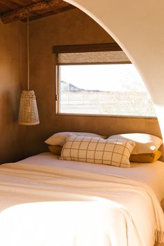 a bed sitting under a window next to a lamp