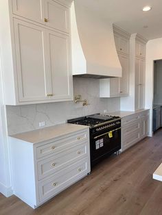 a kitchen with white cabinets and black stove top oven in the middle of the room