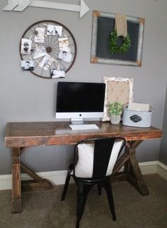 a desk with a computer on top of it in front of a clock and pictures