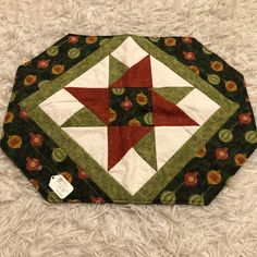 a green and red quilted table topper on white furnishing with an ornament in the center