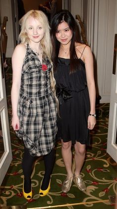 two young women standing next to each other on a carpeted floor in front of doorways