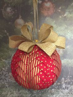 a red ornament with a gold bow hanging from it's side on a table