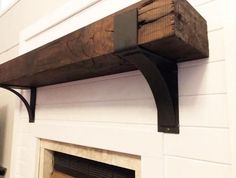 a fire place with a wooden shelf above it and a white wall behind the fireplace