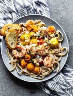 a plate of pasta with shrimp and tomatoes