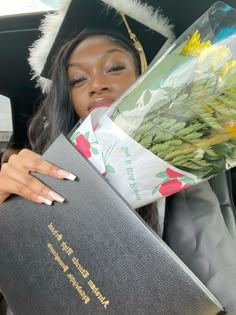 a woman in a car holding flowers and a book