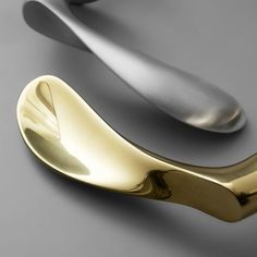 two gold and silver spoons sitting next to each other on a gray surface,