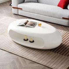 a living room with a couch, coffee table and book on the floor in front of it