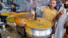 two men are cooking food in large pots