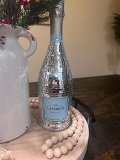 a bottle of champagne sitting on top of a wooden table next to a white vase