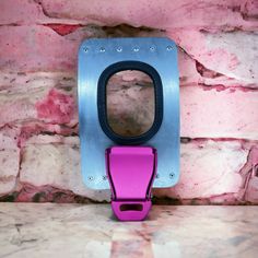 a pink and blue holder on a brick wall