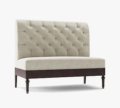 an upholstered couch with wooden legs and buttons on the back, viewed from the front