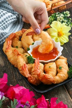 a person dipping sauce on some shrimp