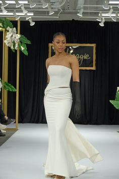 a woman walking down a runway in a white dress